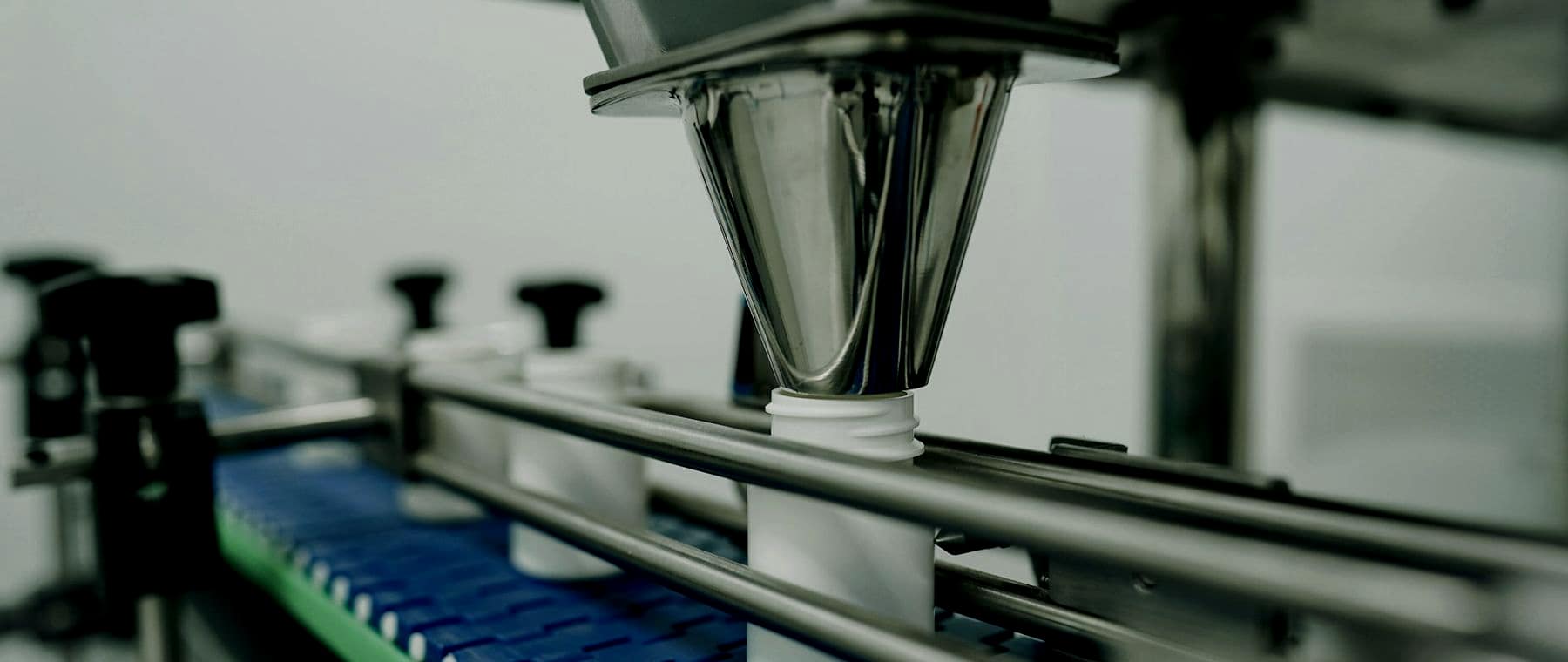 Close-up of a beverage filling head above a conveyor